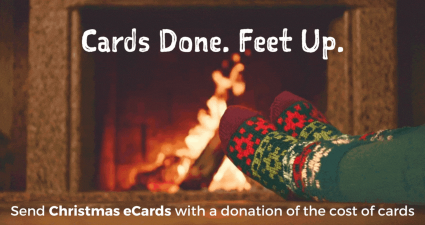 Someone in cosy Christmas socks is warming their toes by a flickering fire. Text reads : cards done. feet up. Send eCards for Christmas with a donation of the cost of the cards