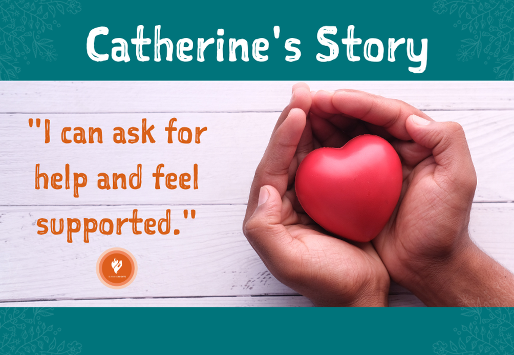An image titled 'Catherine's Story' with the text 'I can ask for help and feel supported.' A pair of hands holds a red heart against a white wooden background, signifying care and support.