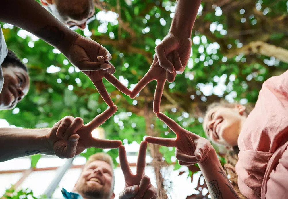 A group of smiling volunteers make a star shape with their hands.