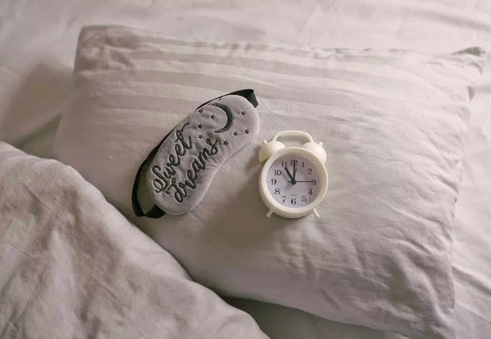 Pillow with a sleep mask and alarm clock on top