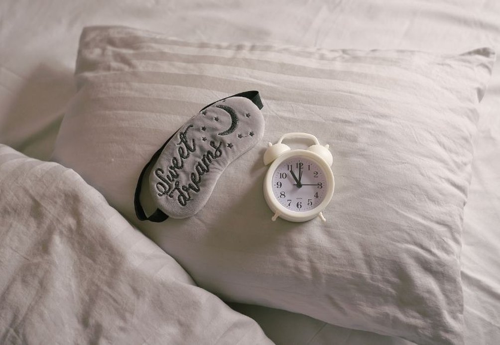 Pillow with a sleep mask and alarm clock on top