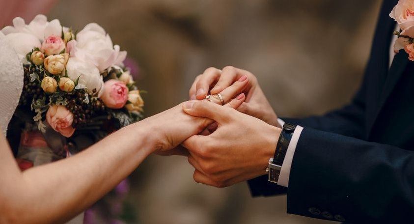 A close up of a couple's hands as they exchange rings during a wedding ceremony