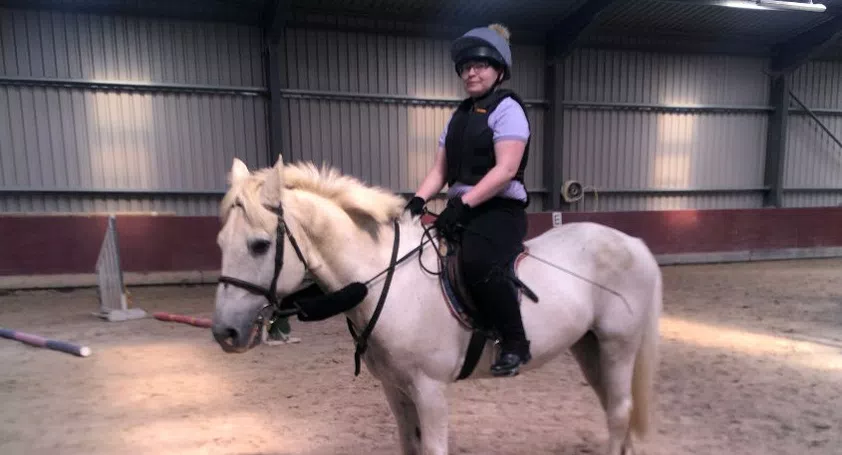 Woman using magnetic stirrups on a grey pony.