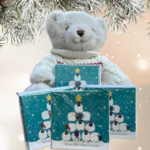 Christmas fir background with 4 packs of cards with sheep on the front in a pyramid shape.