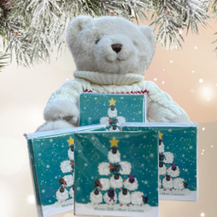 Christmas fir background with 4 packs of cards with sheep on the front in a pyramid shape.