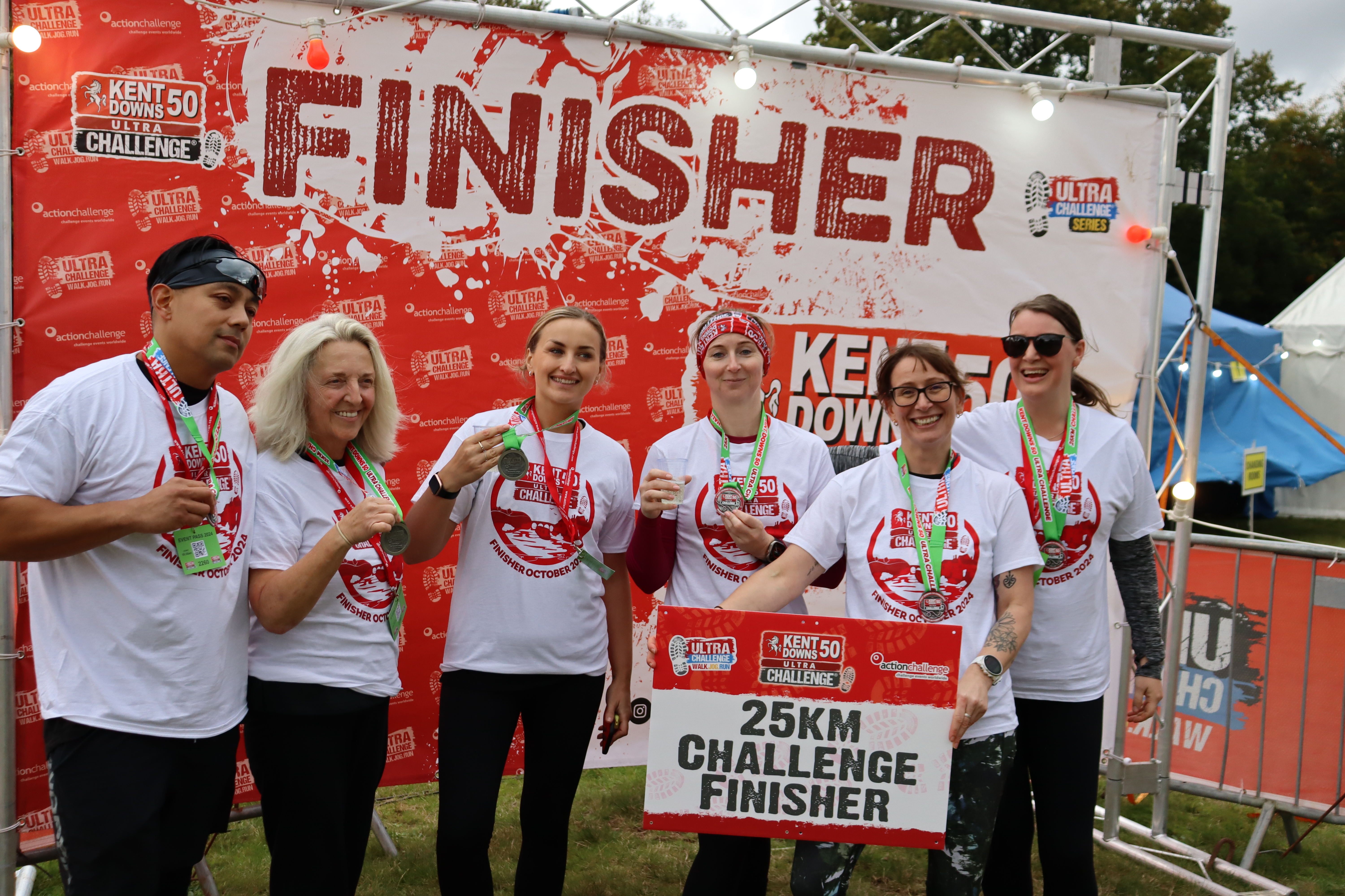 Kent Downs 50 Ultra Challenge 2026, photo of participants at the finish line with their medals and a sign that says "25km challenge finisher"