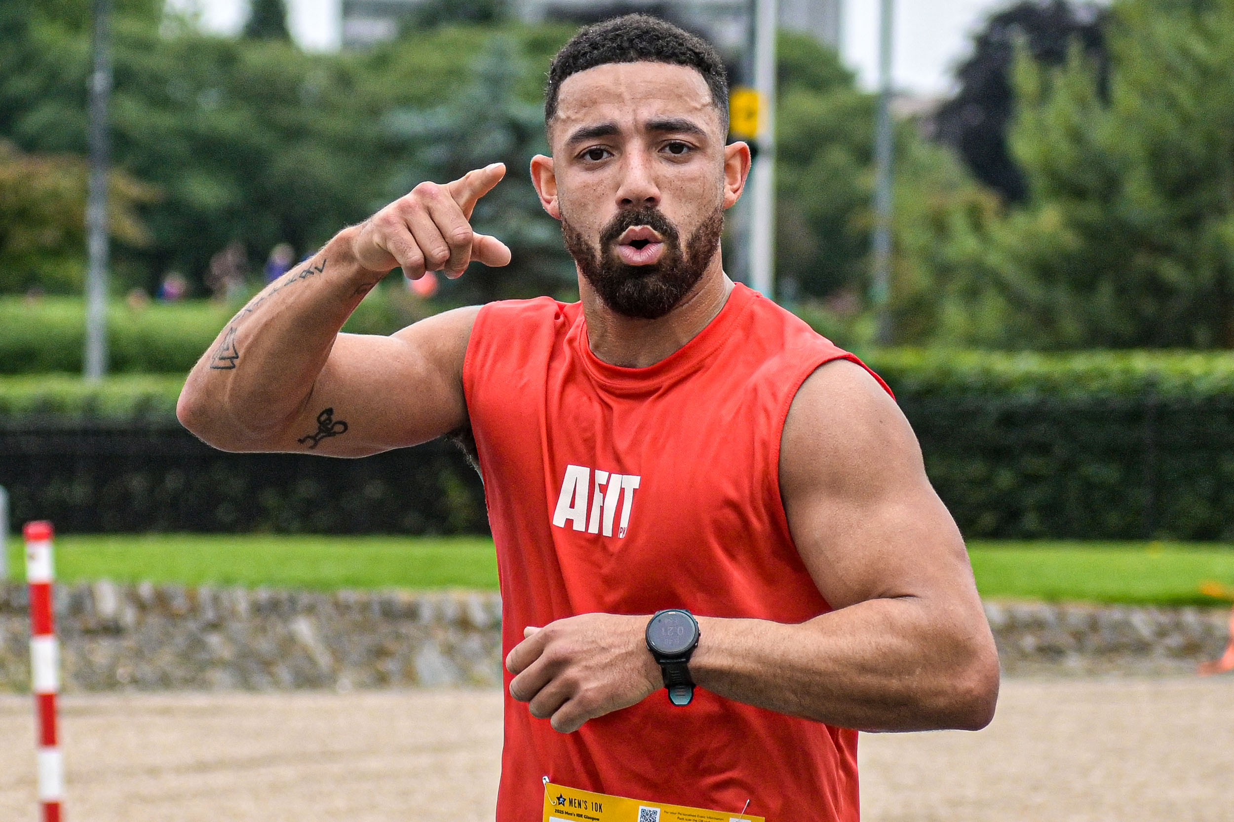 2026 Men’s 10K Glasgow, photo of event participant in an orange vest looking and pointing at the camera