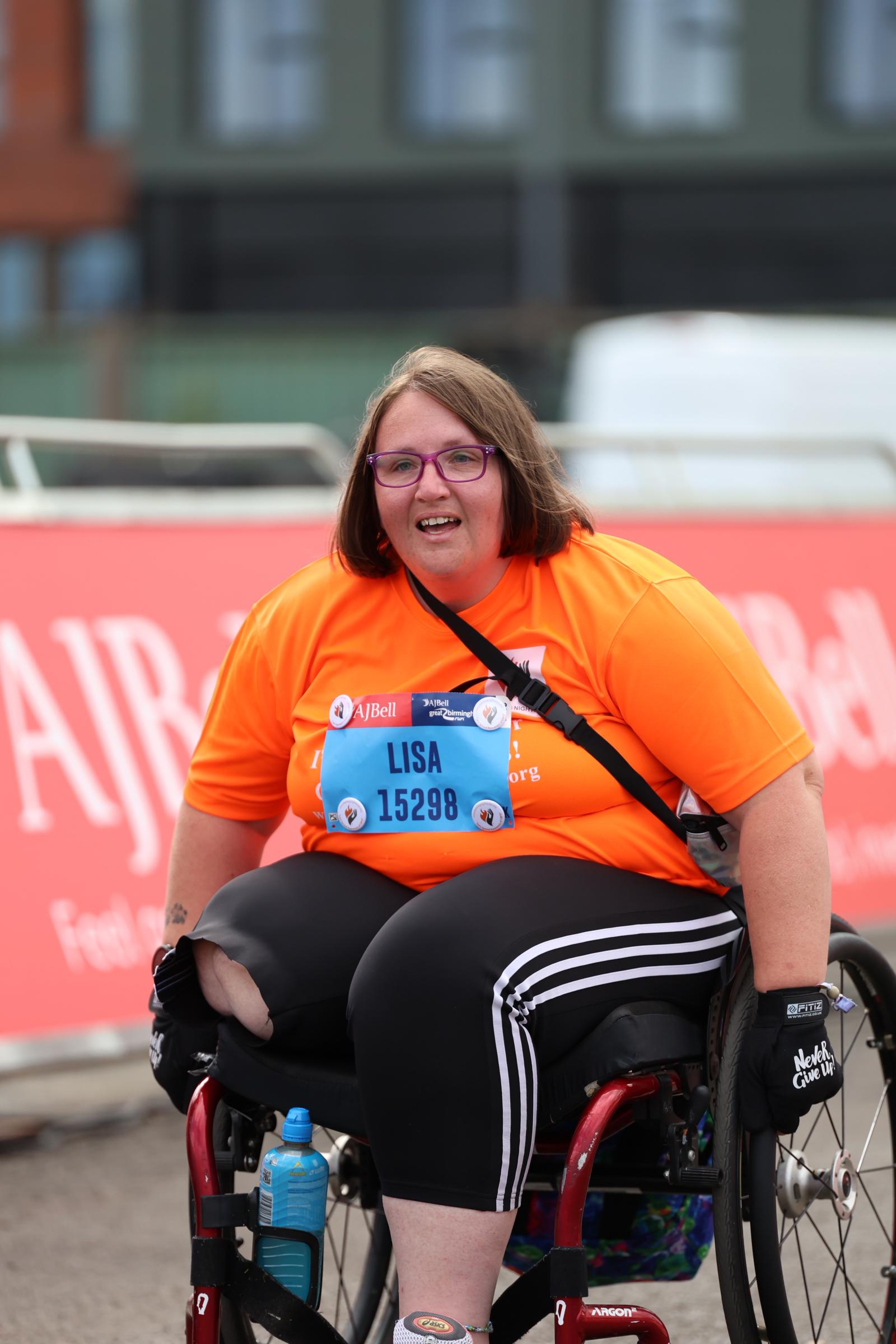 white woman in a wheelchair wearing an orange t-shirt